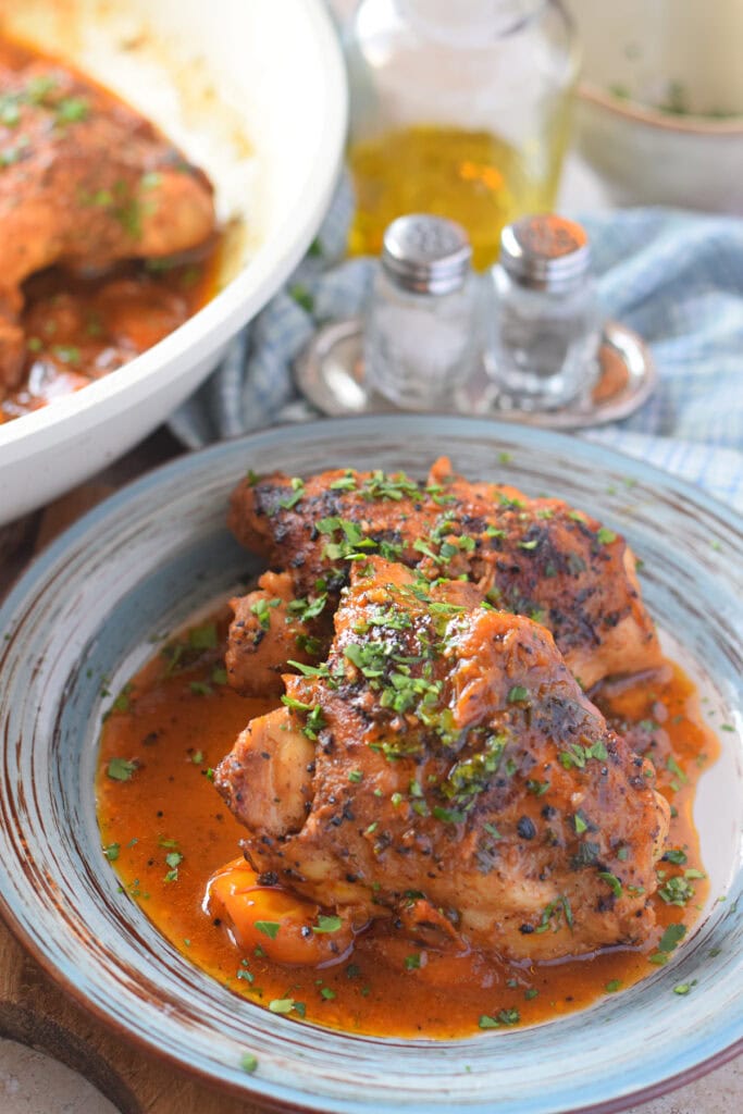 Close up of chicken thighs on a blue rimmed plate.