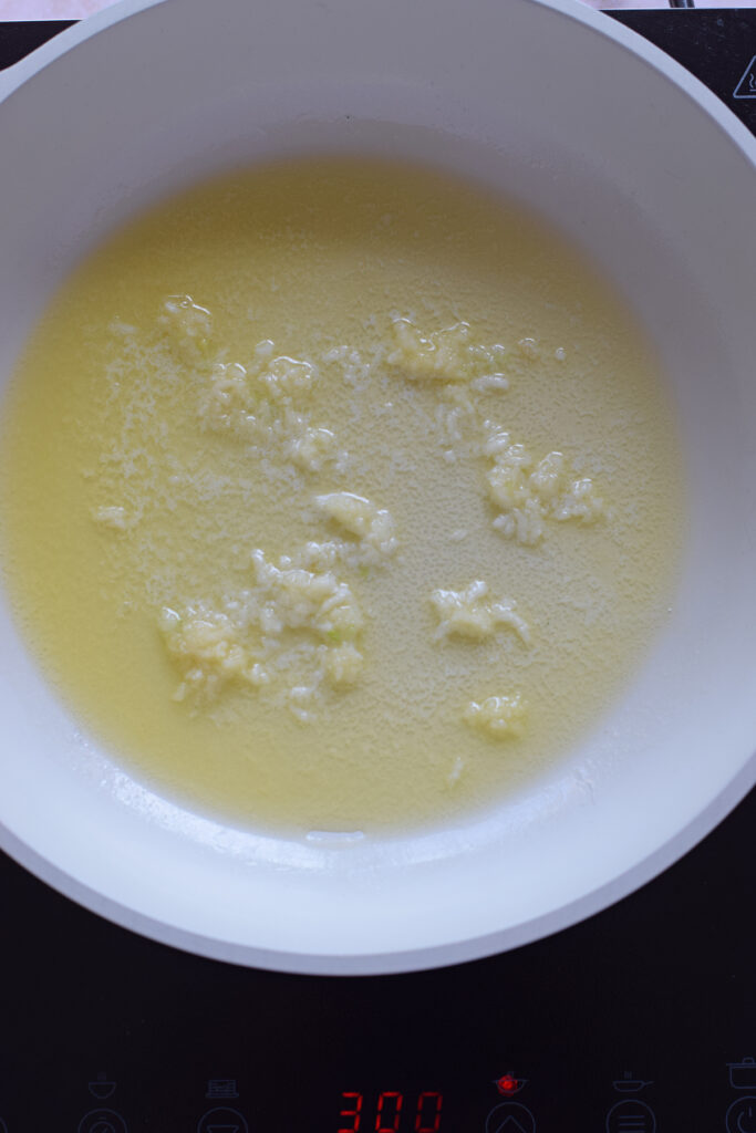 Heating butter and garlic in a white skillet.