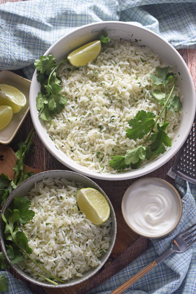 White rice with lime and cilantro in white serving bowls.