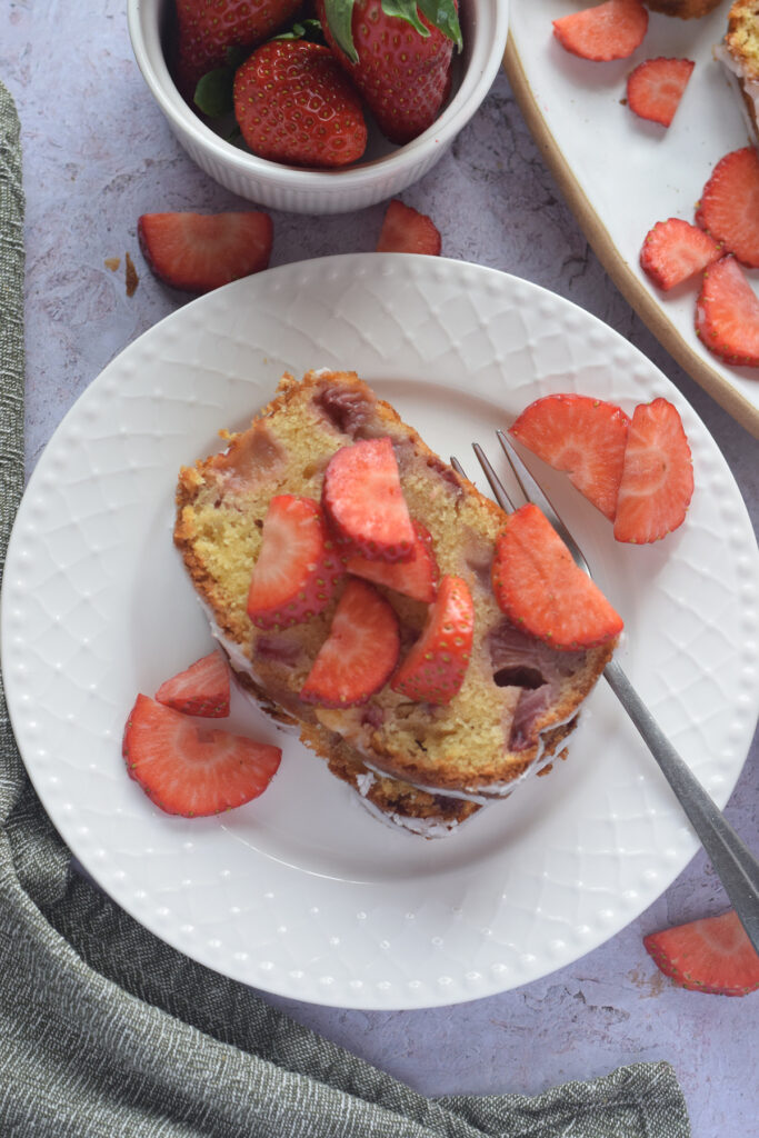 A slice of strawberry loaf cake on a white plate.
