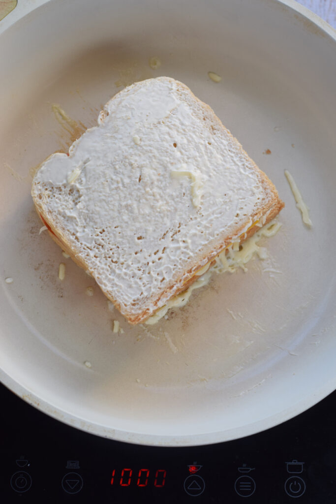 Cooking a grilled cheese in a white skillet.