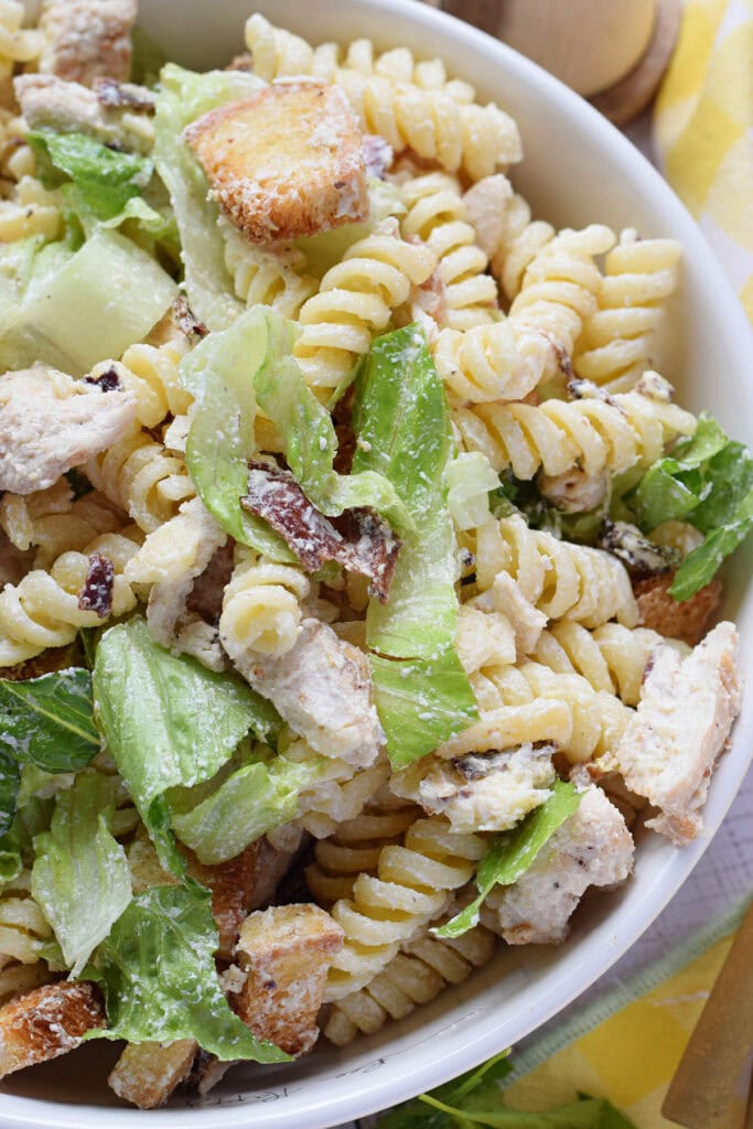 Close up of chicken pasta salad in a white bowl.