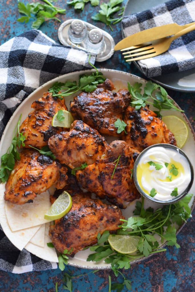 Yogurt marinated chicken on a plate with a dip.