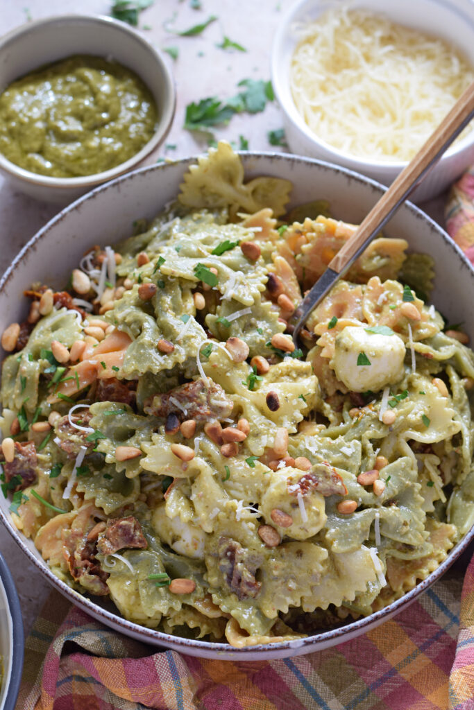 Close up of a green pesto pasta salad in a bowl.