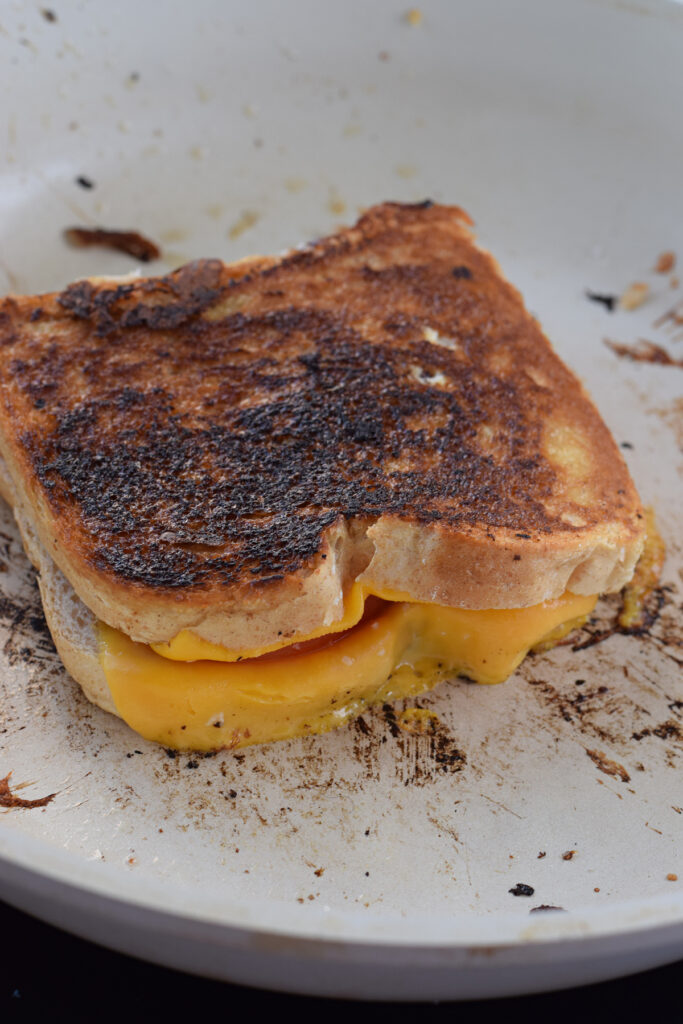 Cooking a grilled cheese in a white skillet.