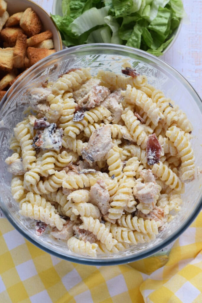 Chicken caesar pasta salad in a glass bowl.
