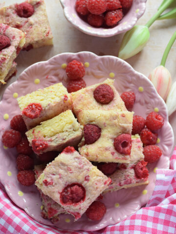 Raspberry cake squares on a pink plate.
