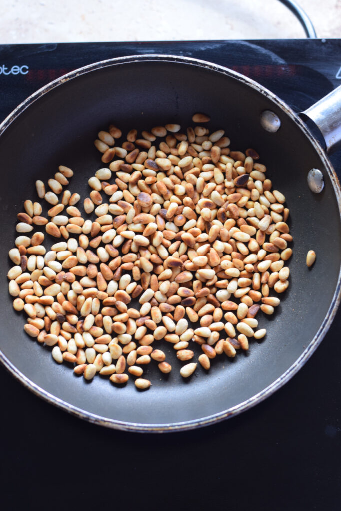 Toasted pine nuts in a small skillet.