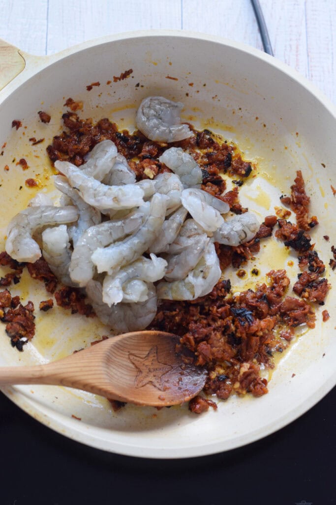 Adding shrimp to a skillet.