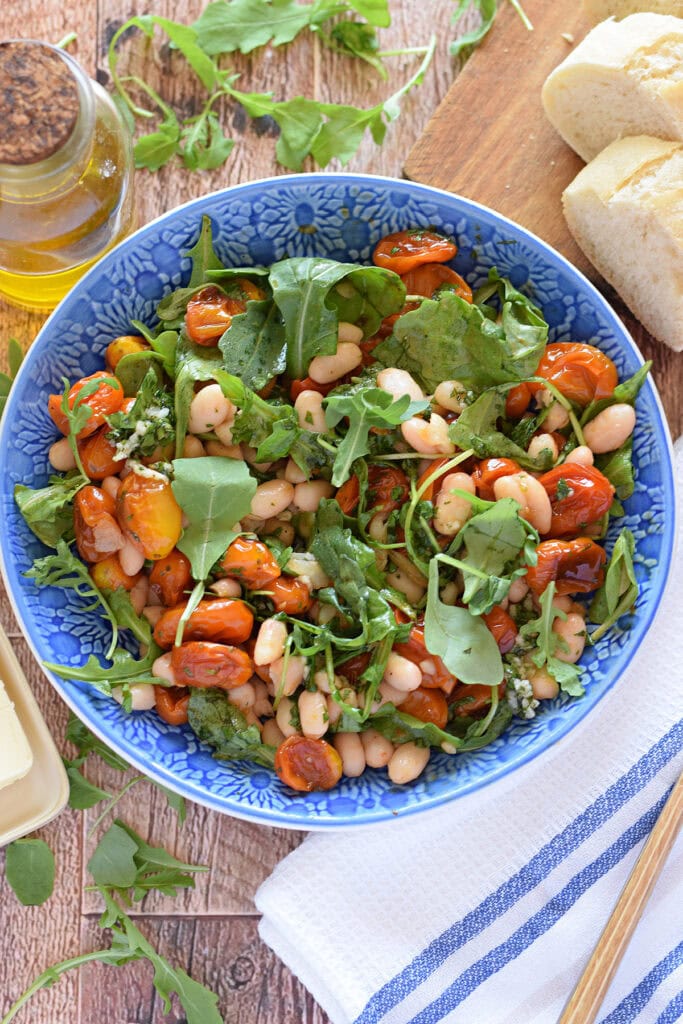 A cannelloni bean and cherry tomato salad in a blue bowl.
