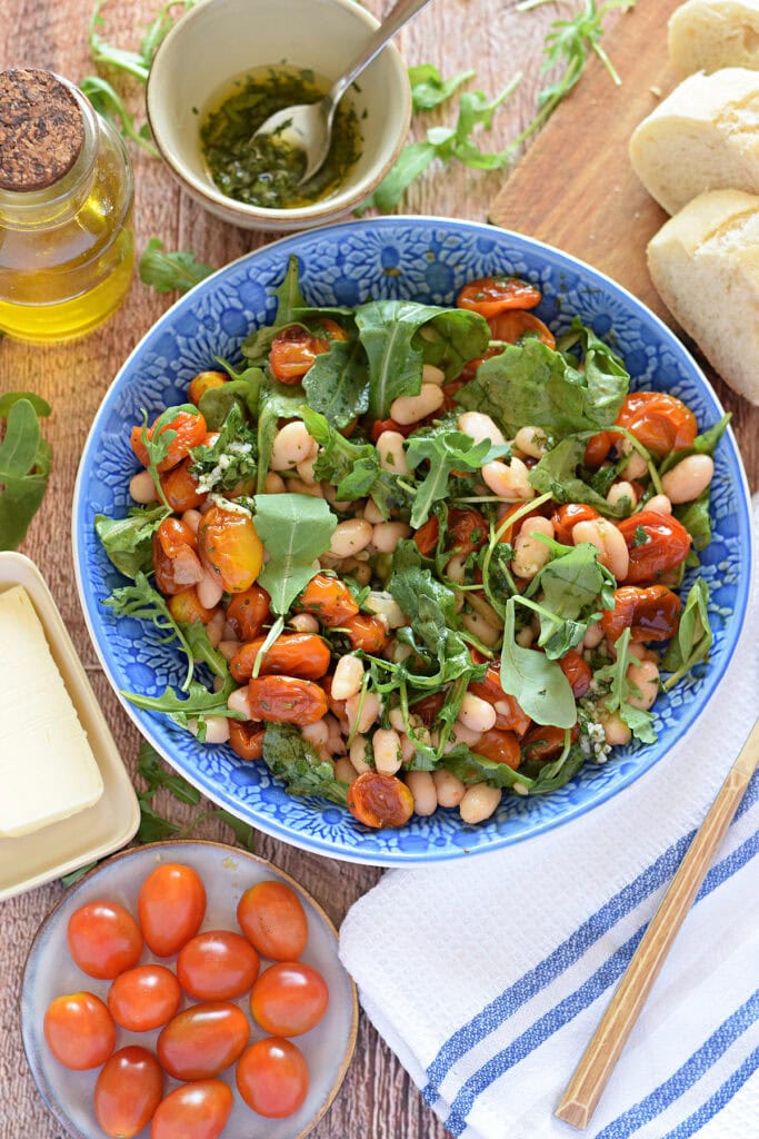 Cherry tomato and bean salad in a blue bowl with bread.