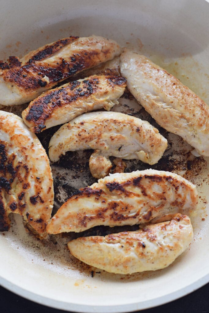 Cooking chicken tenders in a skillet.