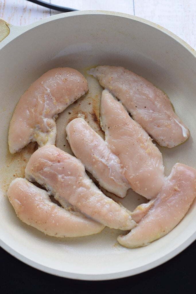 Cooking chicken tenders in a skillet.