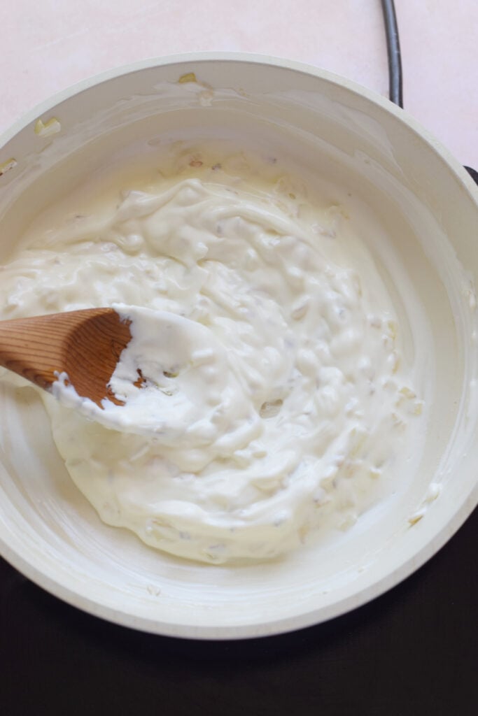 Adding cream cheese to a skillet.