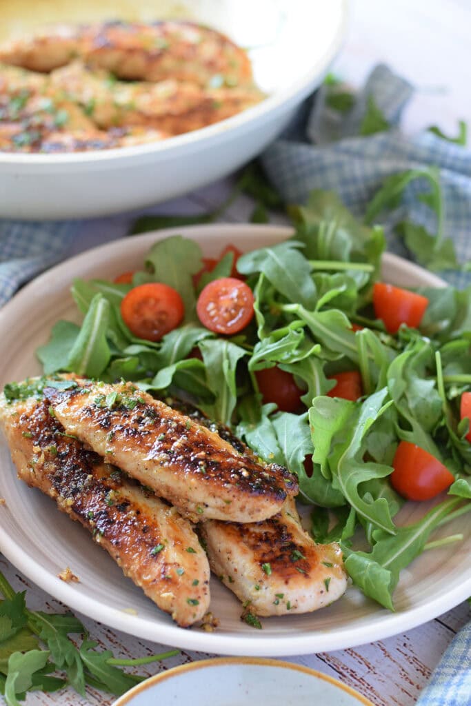 Close up of garlic chicken tenders with a salad.