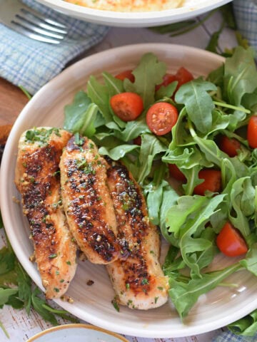 Chicken tenders on a plate with a salad.