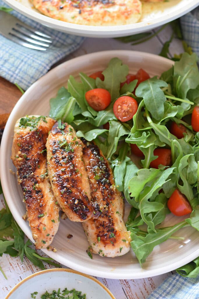 Chicken tenders on a plate with a salad.