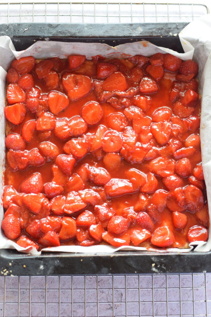 Strawberry filling over a cookie base in a baking dish.