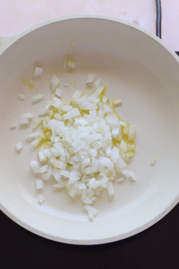 Adding onions to a skillet.