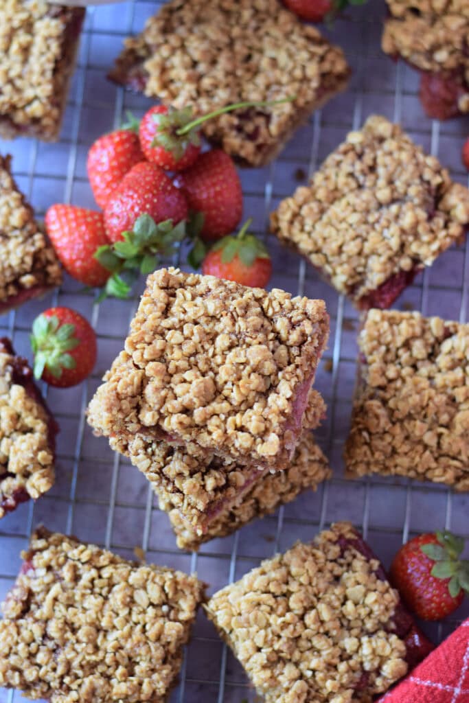 Strawberry oat bars on a cooling rack with fresh strawberries.