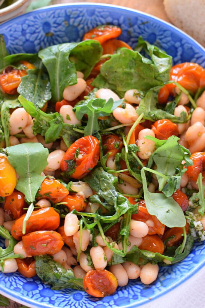 Close up of a bean and tomato salad in a blue bowl.