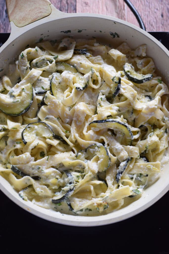 Zucchini and ricotta pasta dish in a white skillet.
