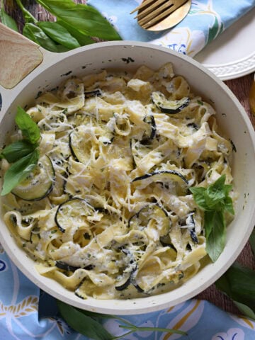 Zucchini pasta dish in a white skillet.