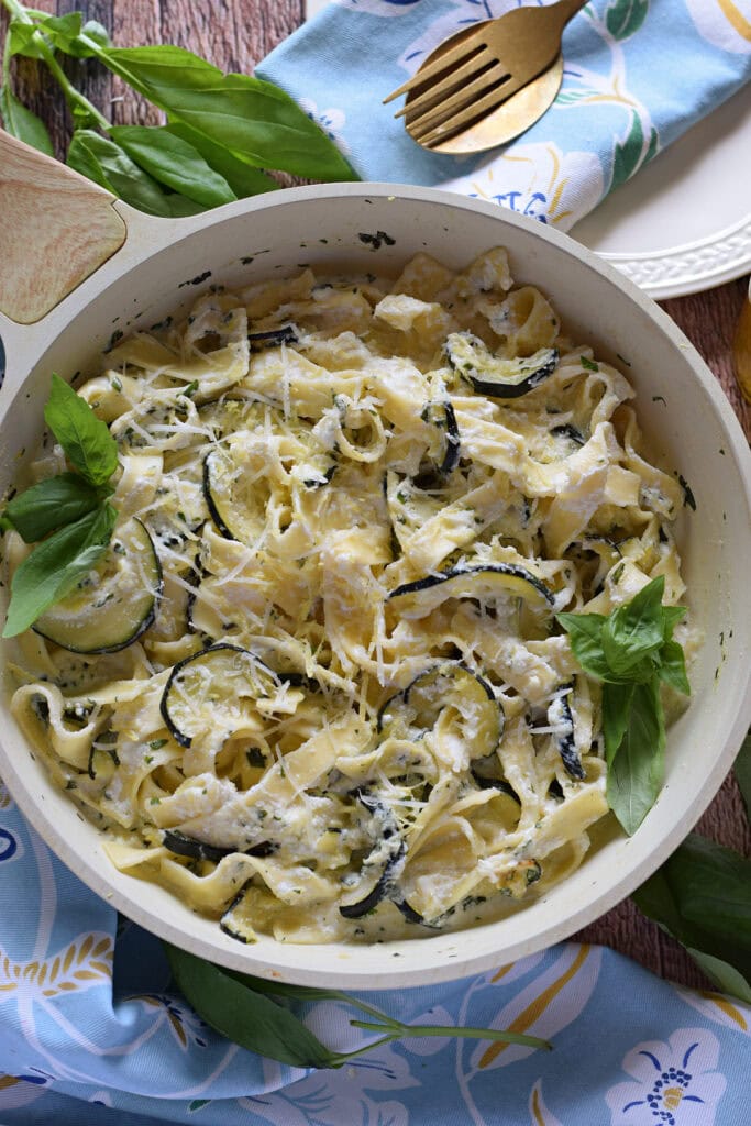 Zucchini pasta dish in a white skillet.
