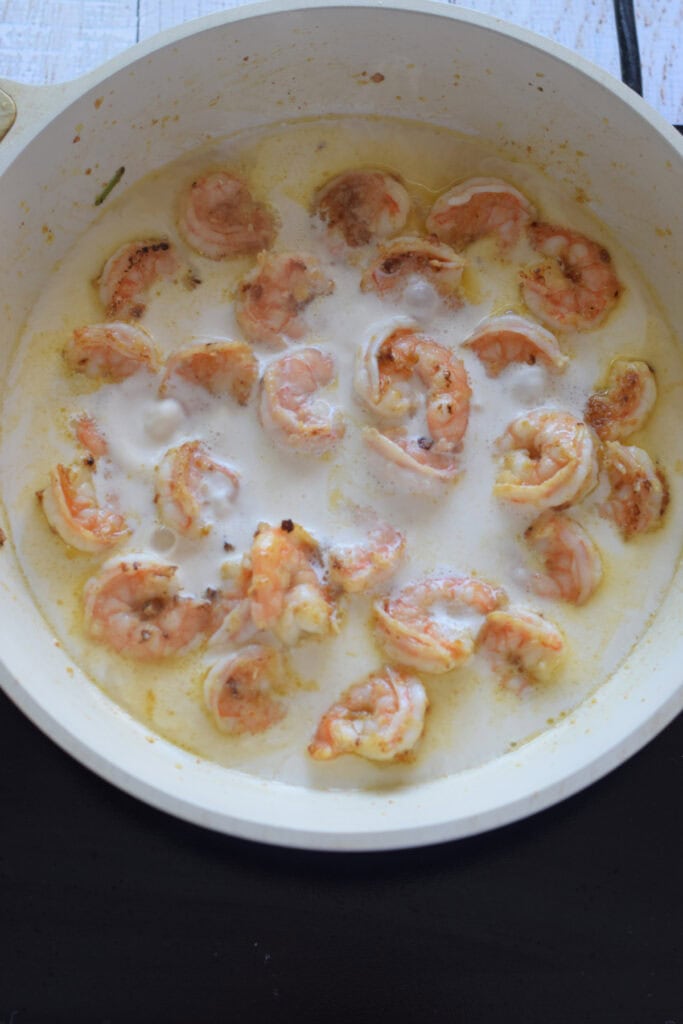 Shrimp in a creamy sauce in a skillet.