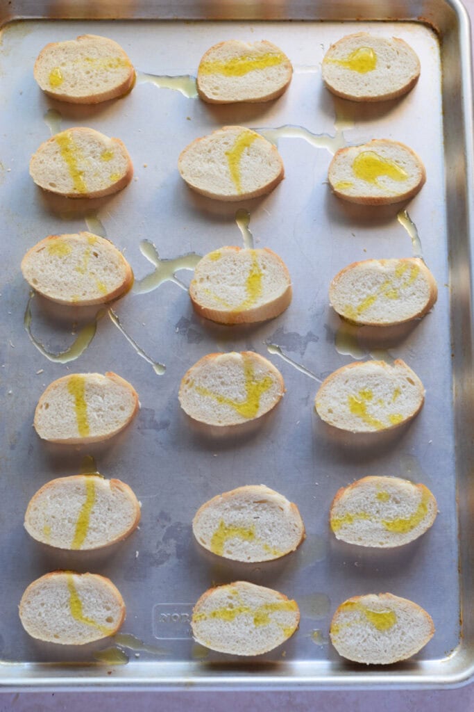 Baguette slices on a baking tray.