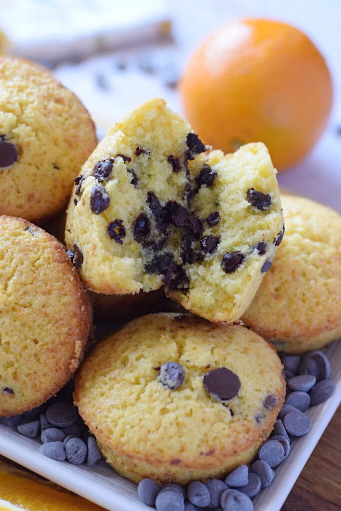 Close up of orange chocolate chip muffins on a white serving plate.