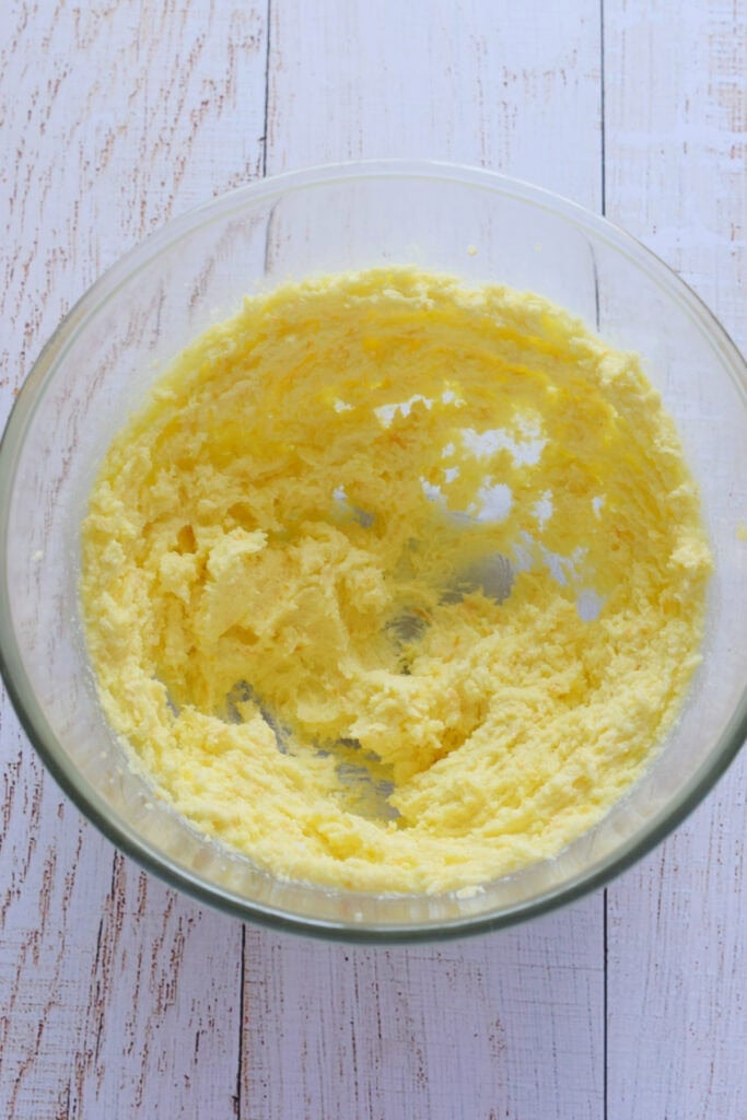 Mixing butter and sugar in a glass bowl.