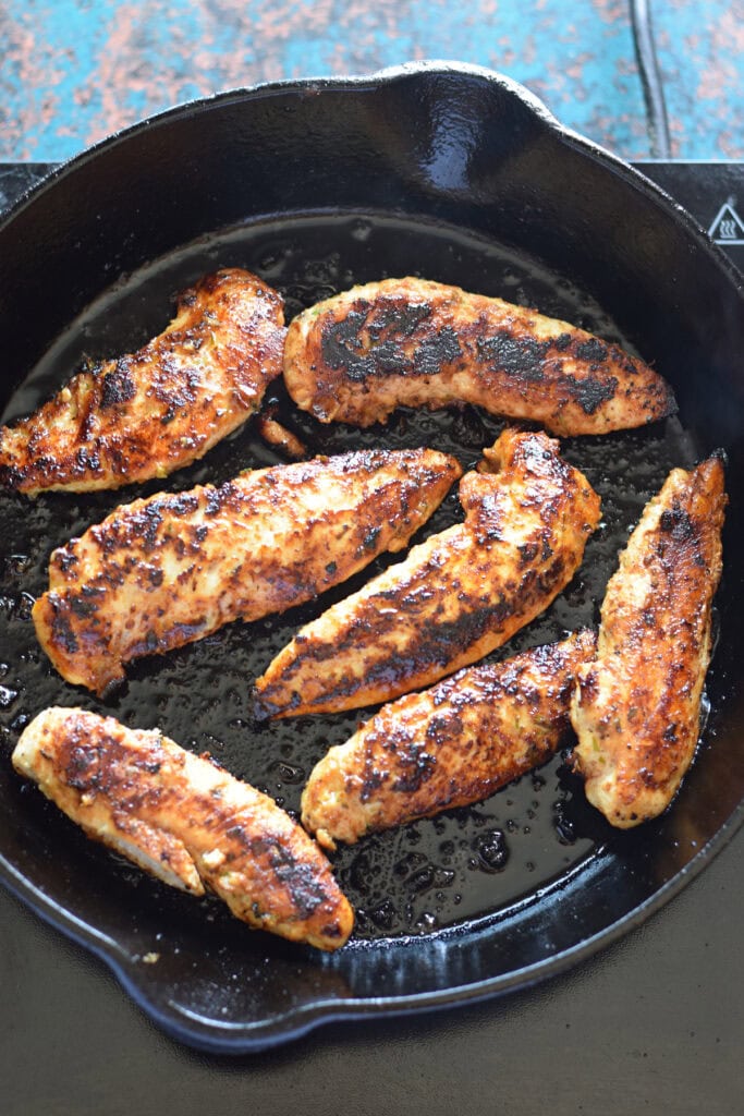 Cooked chicken tenders in a skillet.