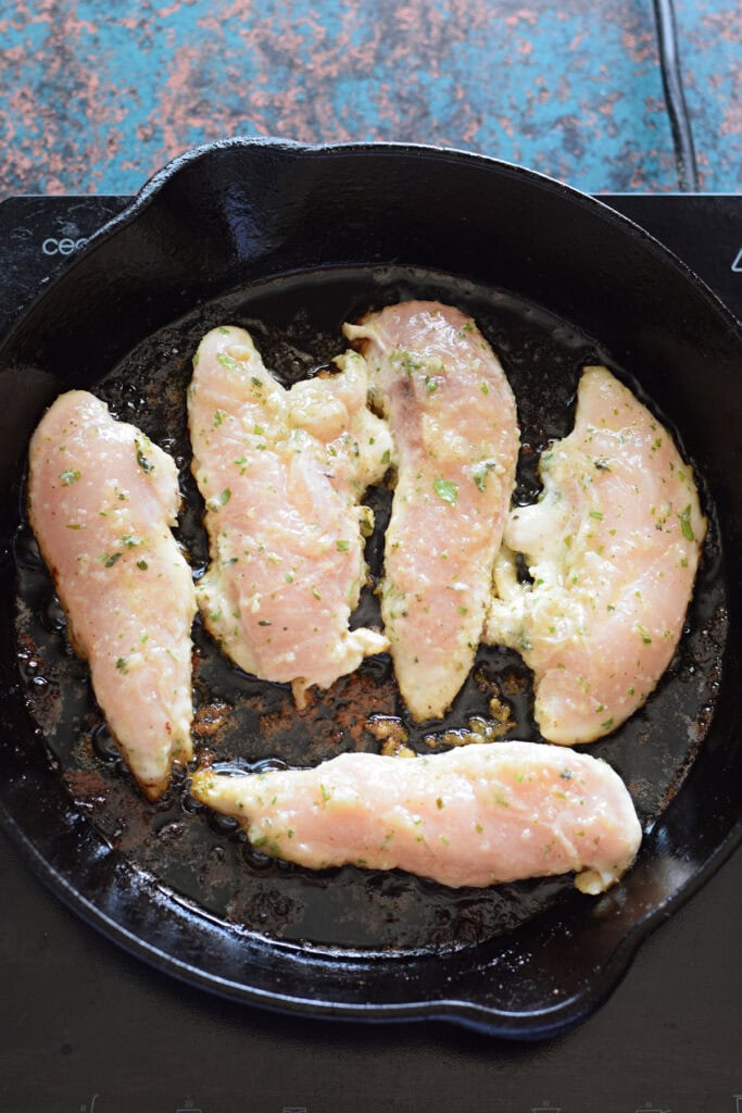 Cooking chicken tenders in a hot skillet.