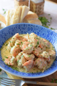Close up of creamy parmesan shrimp on a blue bowl.