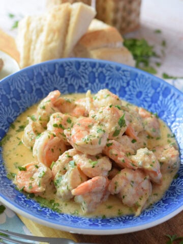 Close up of creamy parmesan shrimp on a blue bowl.
