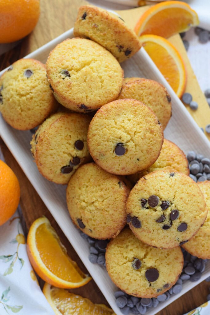Orange chocolate chip muffins on a white serving plate.