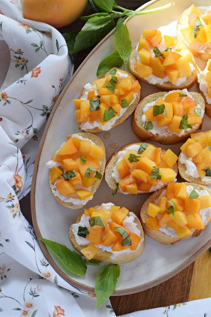 Peach crostini with ricotta cheese on a tray.