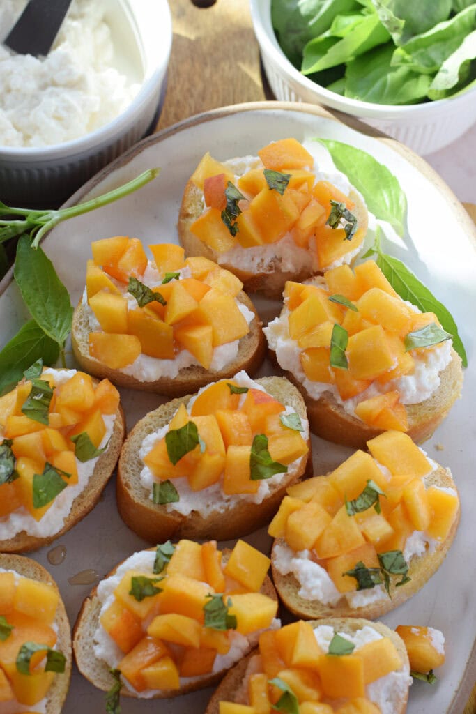 Peach and ricotta crostini on a serving plate.