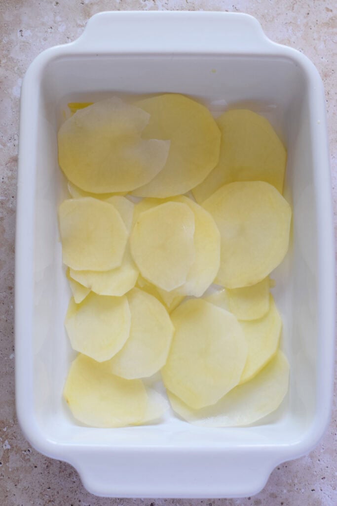A layer of potatoes at the bottom.