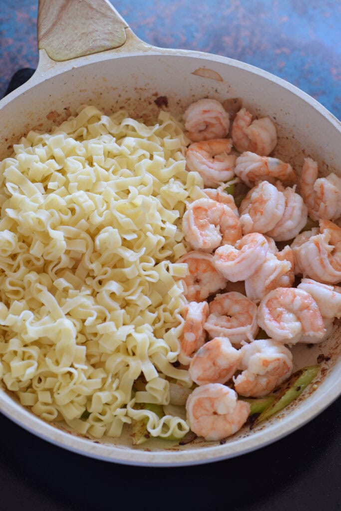 Shrimp and noodles in a white skillet.