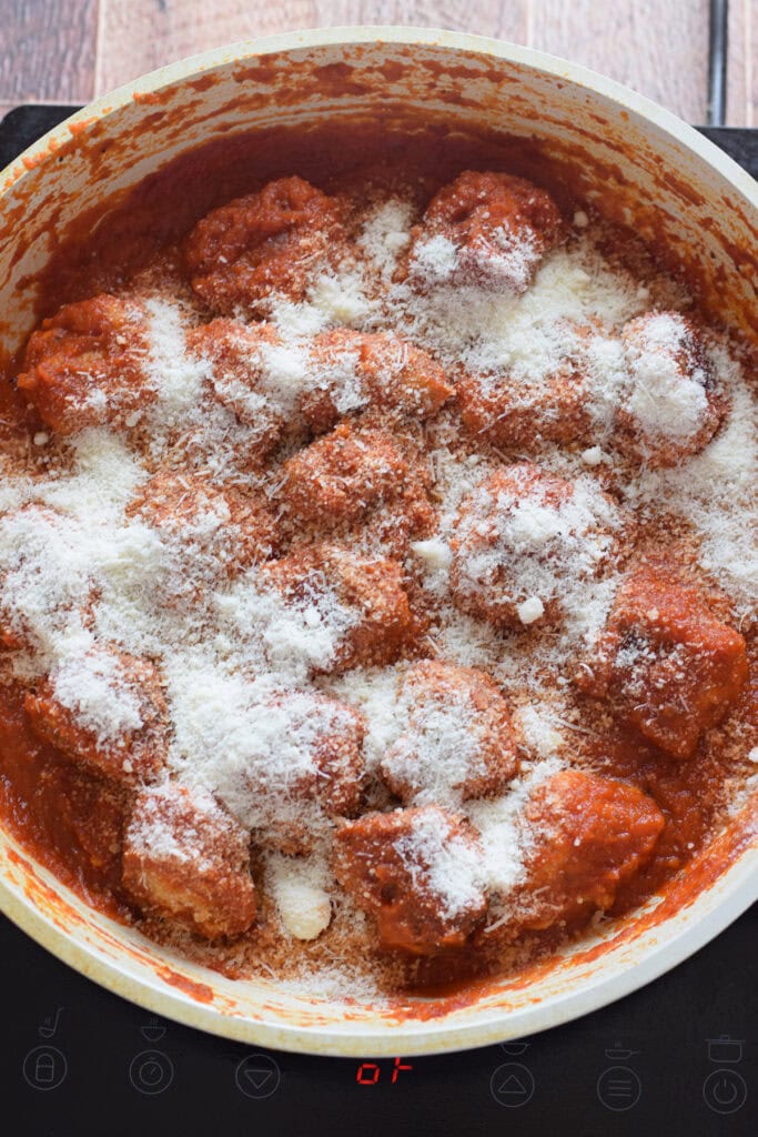 Adding parmesan cheese to meatballs.