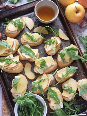 Apple and brie crostini on a baking tray.