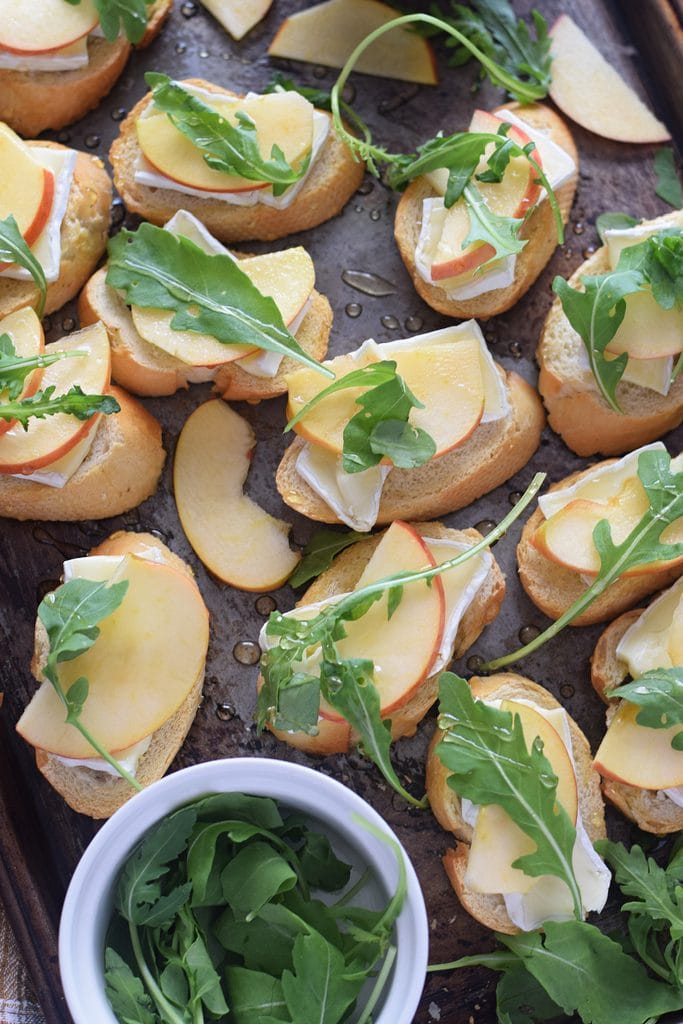 Crostini with apples and brie cheese on a baking tray.