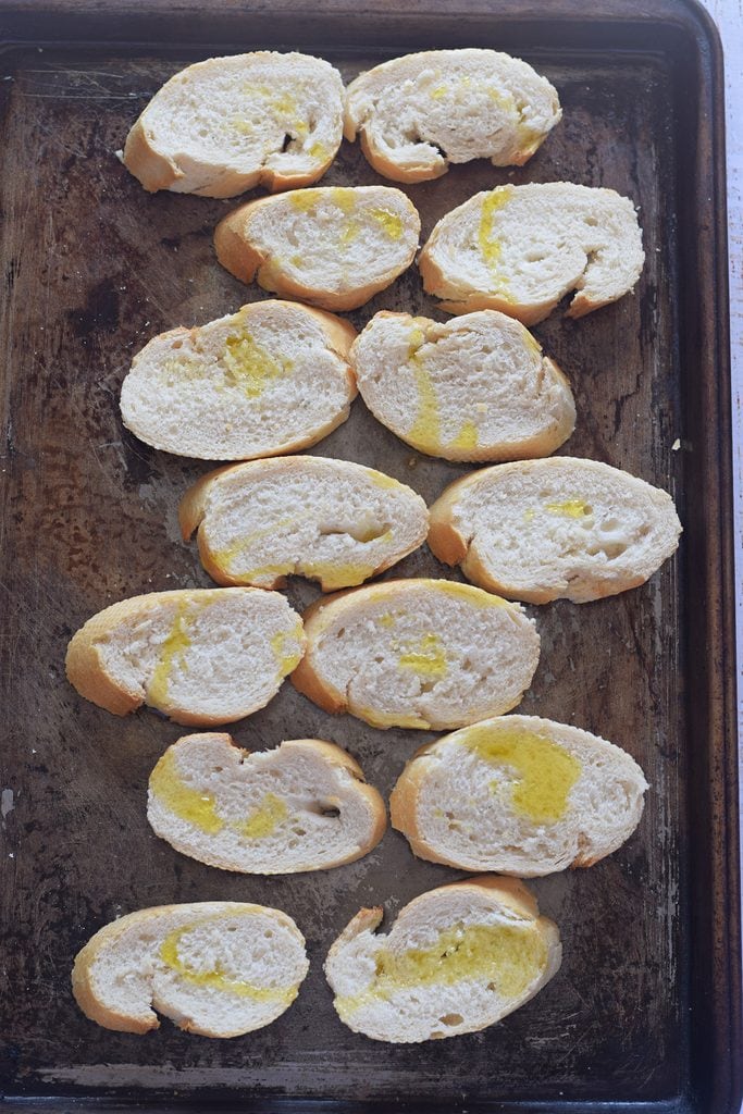 Baguette bread slices on a baking tray.