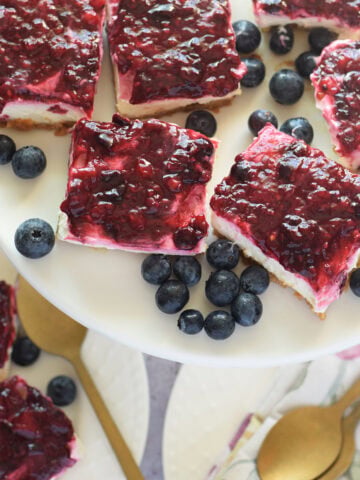 Berry cheesecake bars on a white plate.