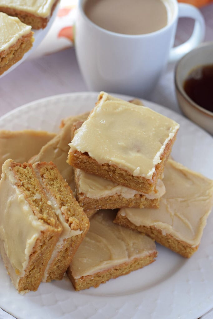 A stack of maple glazed blondies on a white serving plate.