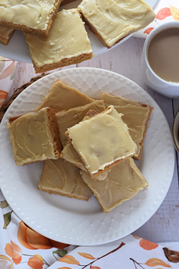 Blondies on a plate with a cup of coffee.