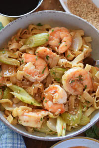Close up of a shrimp and noodle stir fry in a dish.