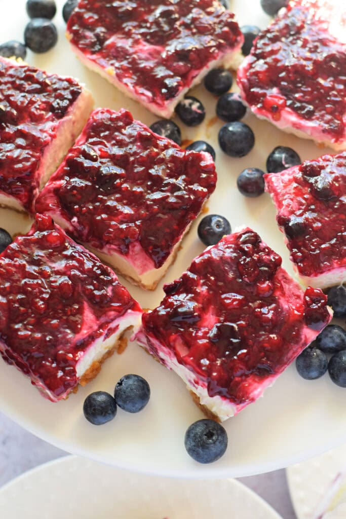 No bake berry cheesecake bars on a white plate.